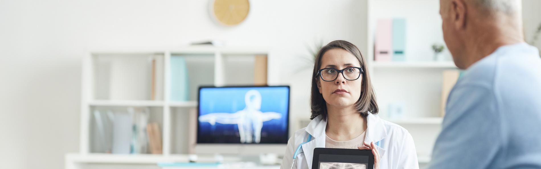 Ärztin zeigt einem Patienten sein Röntgenbild