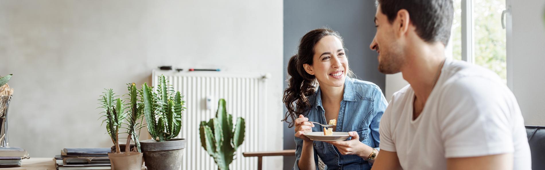 Junges Paar sitzt kuchenessend auf Sofa