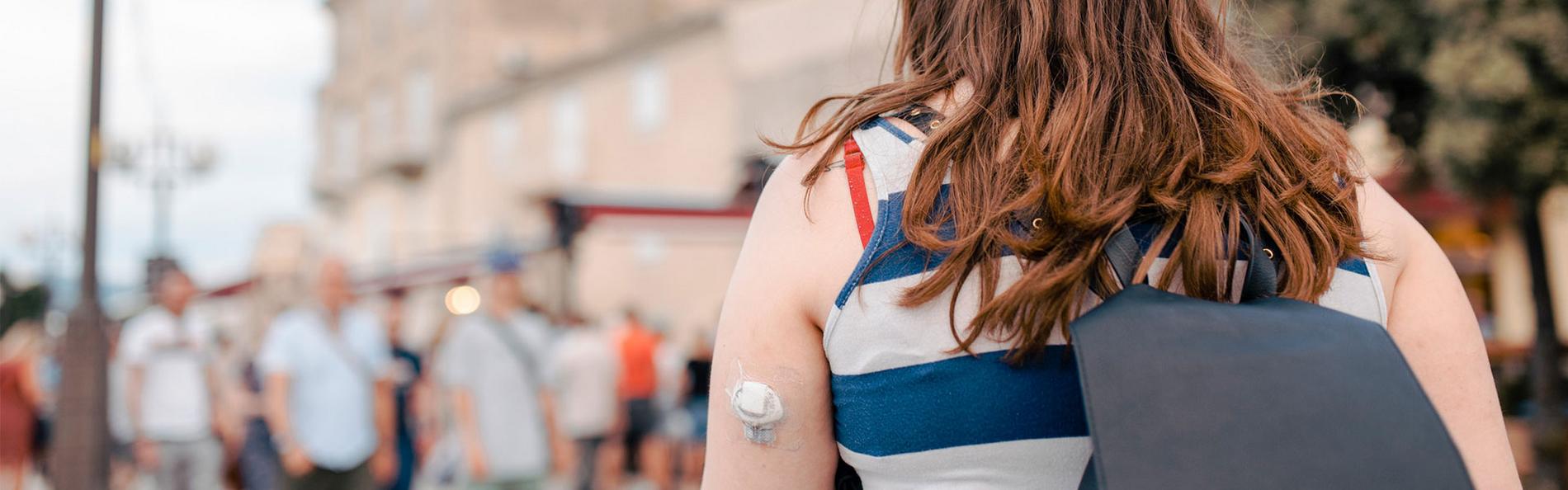 Junge Frau mit Glucose-Monitor am Arm